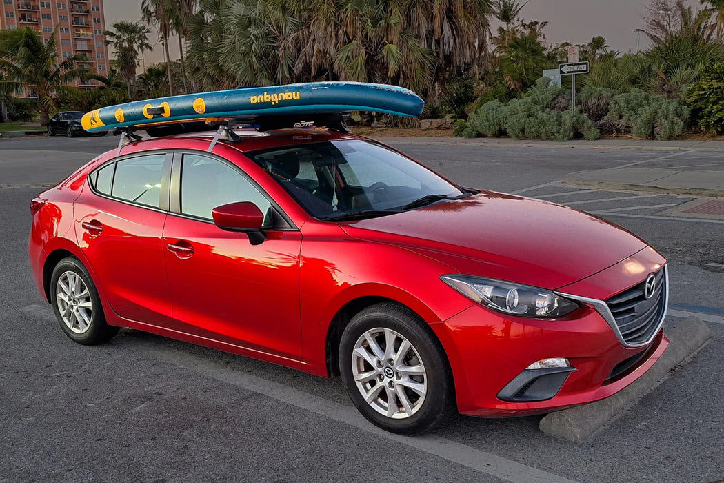 Red car with a surfboard on top in a parking lot