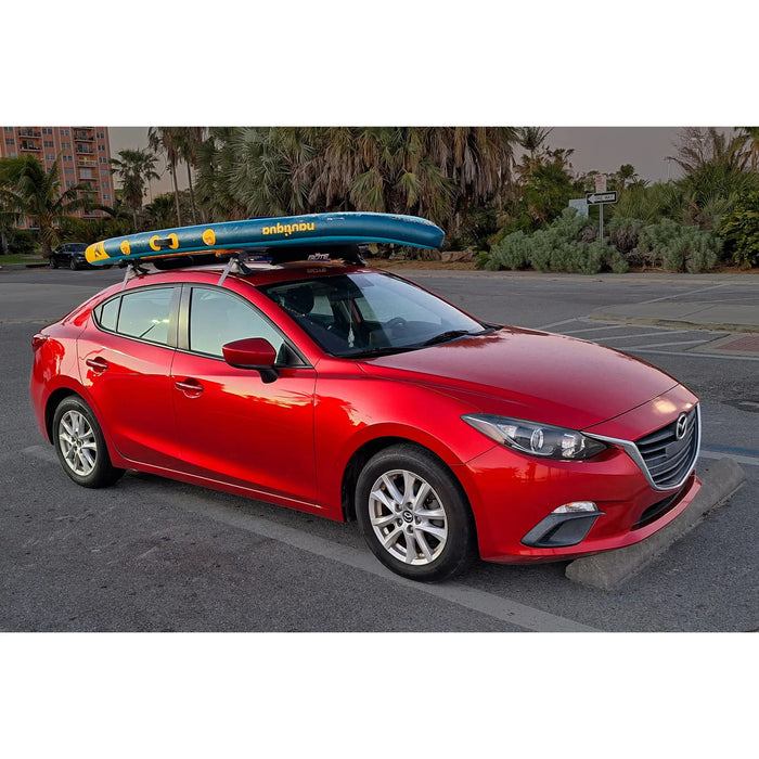 Red car with a surfboard on top in a parking lot