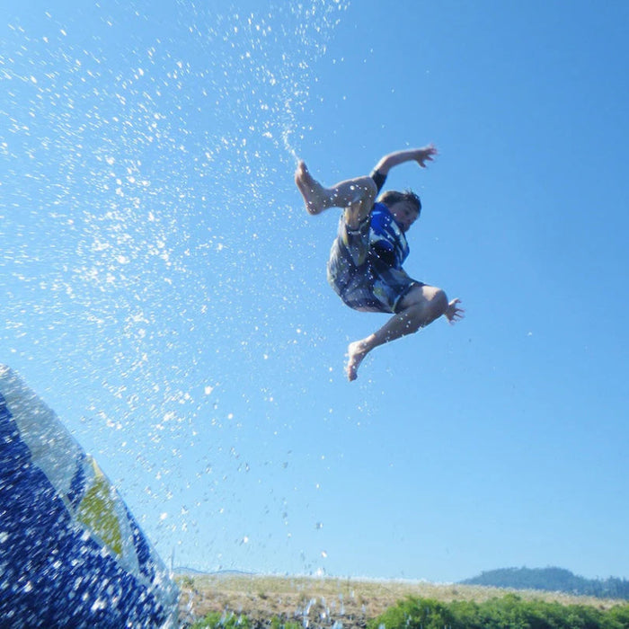 Person jumping off a diving board with water splashes against a clear blue sky.
