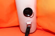 Close-up of a pink inflatable seat with a black strap and valve on an orange background