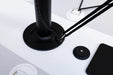 Black adjustable desk lamp on a white surface with a smartphone and mouse pad.