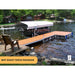Wooden dock with lounge chair on a lake with cabins in the background, featuring Patriot Docks branding.