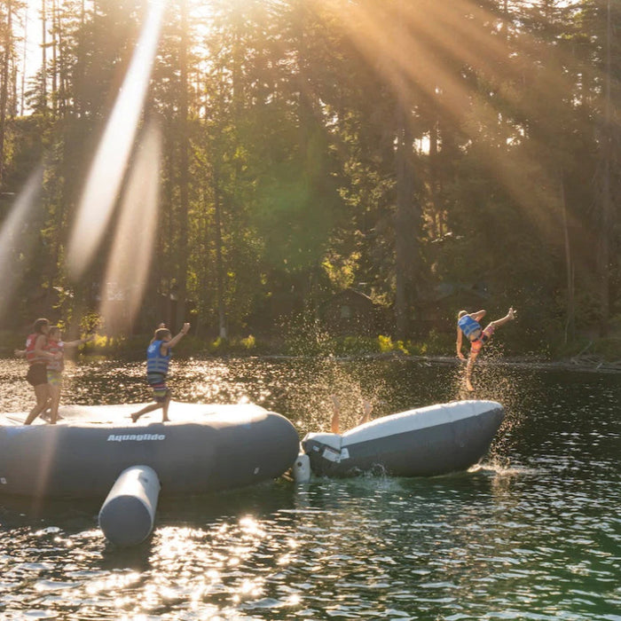 People on inflatable rafts in a lake with sunbeams through trees